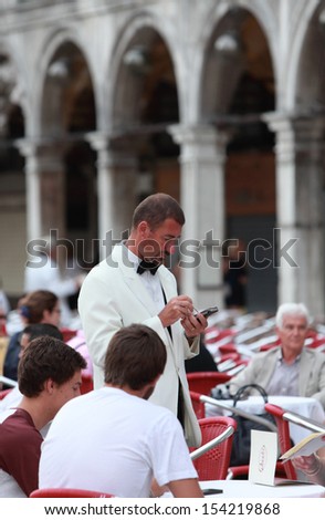 VENICE, ITALY-JUL 30: Unidentified waiter takes order of guests using a notepad, on a terrace of an elegant restaurant in St.Mark Square on July 30, 2011 in Venice.