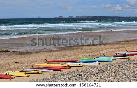 Colorful surf boards on a beach in Birttany.In the distance is Pen Hir Cape.