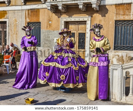 VENICE-FEB 18:Image of a group of three persons wearing violet costumes and masks on February 18, 2012 in Venice.In 2014 the Venice Carnival will be held between February 15- March 4