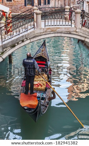 VENICE-FEB 18:A gondolier in a gondola passing under a bridge on a small canal,during the Carnival on February 18, 2012 in Venice.Gondola is the major mode of touristic transport in Venice, Italy.