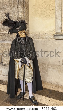 VENICE-MAR 02: Unidentified person specifically disguised wearing a Bauta mask poses near the walls of The Doge\'s Palace on March 02,2014 in Venice, Italy, during the Carnival days.