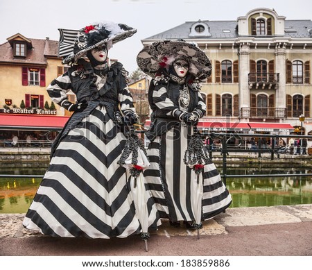 ANNECY, FRANCE,MAR 15:Two persons disguised in fancy costumes poses near a canal in Annecy,France,on March 15 2014.Every year here is held a Venetian Carnival to celebrate the beauty of real Venice.