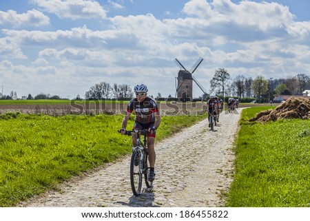 TEMPELUVE,FRANCE-APR 5:Group of  amateur cyclists riding their bicycles on the cobblestone road on April 5, 2014 in Templeuve.Here is the route for Paris-Roubaix the most famous one day cycling race.