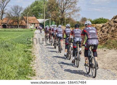 TEMPELUVE,FRANCE-AP R 5:Group of amateur cyclists riding their bicycles on the cobblestone road on April 5, 2014 in Templeuve.Here is the route for Paris-Roubaix the most famous one day cycling race.