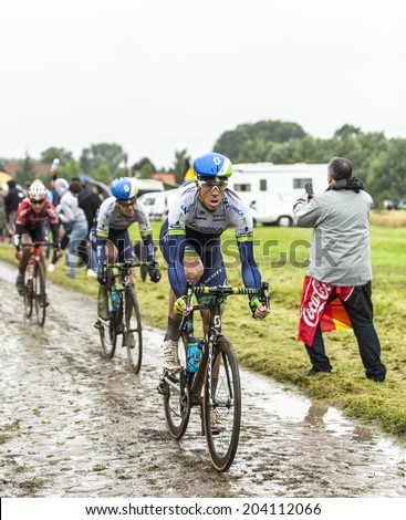 ENNEVELIN, FRANCE - JUL 09:A group of three cyclists led by the cyclist Mathew Hayman (Orica GreenEDGE) riding on a cobbled road during the stage 5 of Le Tour de France in Ennevelin on July 09 2014.