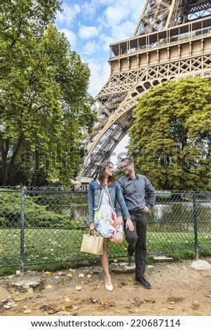 Young happy couple posing in a park close to Eiffel Tower in Paris.