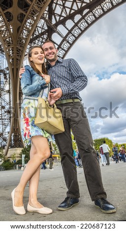 Young happy couple posing under the Eiffel Tower in Paris.