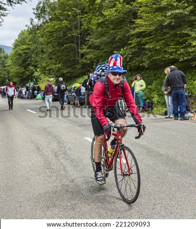LE MARKSTEIN, FRANCE - JUL 13: Funny amateur cyclist wearing a US flag hat climbing the road to the mountain pass Le Markenstein during Le Tour de France on July 13, 2014.