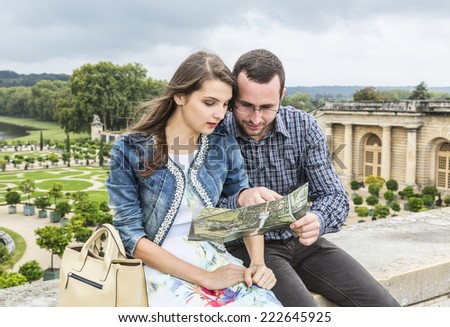 Young couple looking in a map in a beautiful French garden.