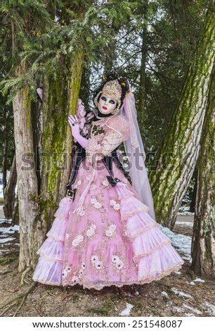 ANNECY,FRANCE- FEB 2013:A person disguised hiding between trees in a forest in Annecy,France,on February 23 2013.Every year here is held a Venetian Carnival to celebrate the beauty of real Venice
