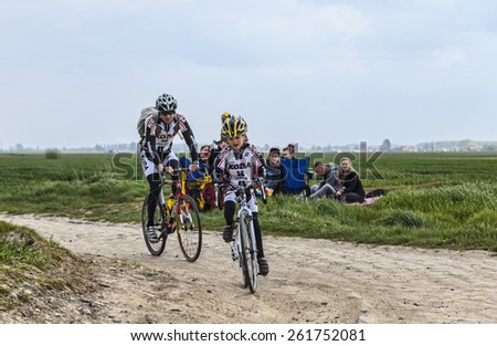 CAMPHIN EN PEVELE,FRANCE-APR 13: Image of a kid and his father cycling on the cobblestone sector Carrefour de Arbre in Camphin-en-Pevele on April 13 2014 during Paris-Roubaix cycling race