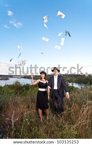 Young couple dressed as 30-s mobsters tossing money into the air