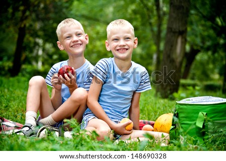 Two smiling twin brothers holding fruits outdoor portrait
