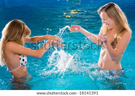 stock photo Two beautiful young girls playing in swimming pool