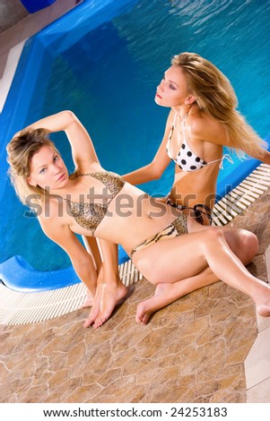 stock photo Two perfect young girls relaxing on water pool border