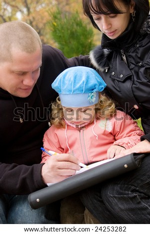 Dad and mom teaching little daughter to write or draw