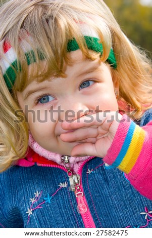 Pretty little girl shyly covering smiling lips with hand