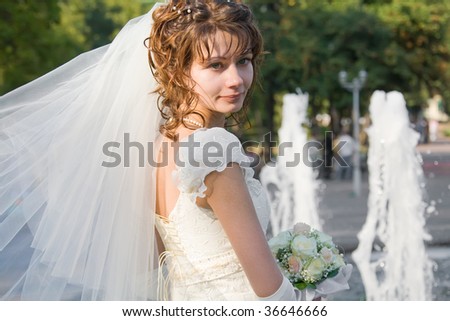 Beautiful young bride with fountain jets on background