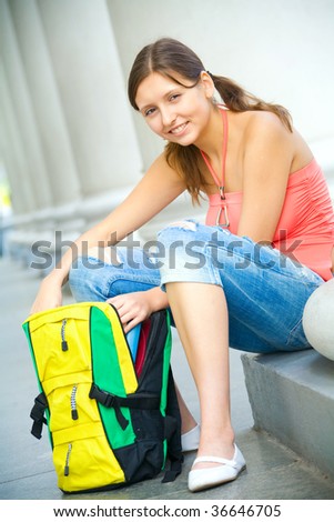 Young smiling college girl opening backpack