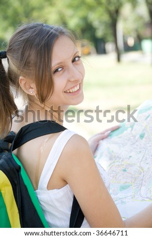Young smiling girl with backpack holding city map