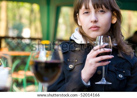 Cute young woman with wine glass sitting in cafeteria