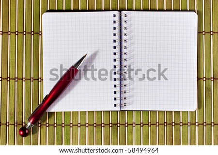 Open notepad with pen over textured bamboo mat for scrapbook related purposes