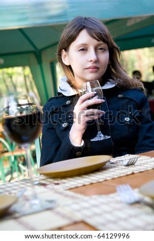 Cute young woman with wine glass sitting in cafeteria