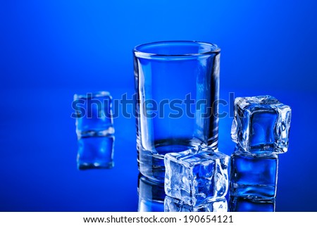 Empty tumbler with ice cubes and reflection