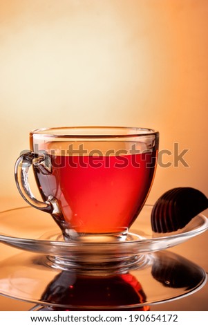 Transparent cup of tea with chocolate candy