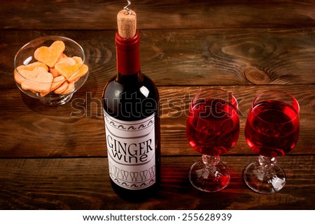 Wine bottle with self made label, glasses and heart shaped cookies on wooden table