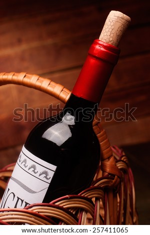 Wine bottle in a basket on wooden table, label is self made