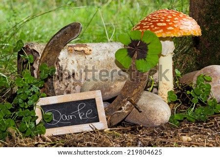 lucky charms with board and writing on forest floor, Thank you