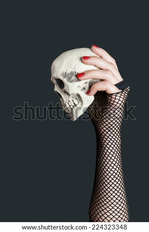 Skull in the hand with red nails on black background. Halloween
