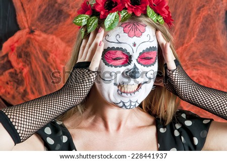Portrait of young blond girl in black dress with Calavera Mexicana makeup mask with emotions of horror on her face