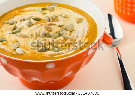 Delicious pumpkin soup in the orange bowl with seeds