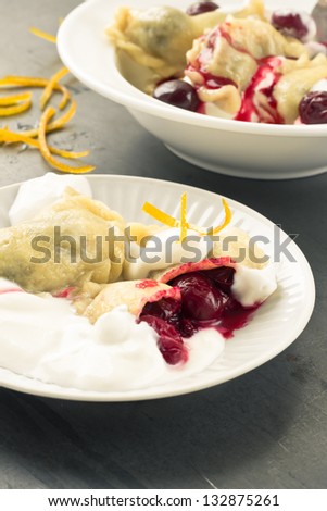 Cherry dumplings with sour cherry and cream on a white plate
