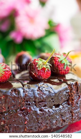 Chocolate cake with chocolate icing on a background of flowers