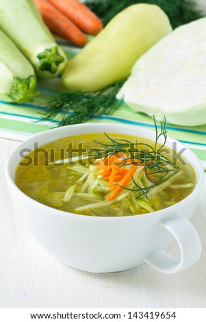 Bowl of vegetable soup with fresh vegetables around