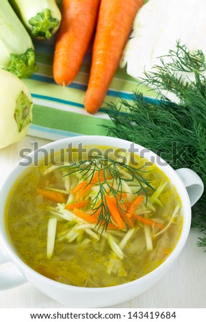 Bowl of vegetable soup with fresh vegetables around