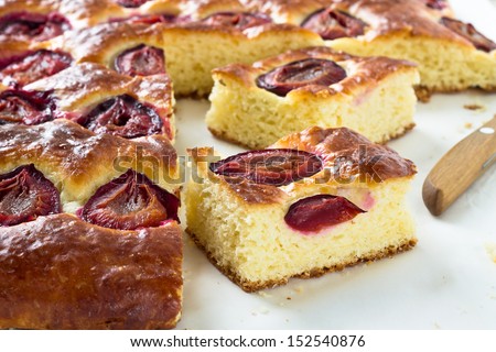 Plum cake and slices of plum cake on a baking paper