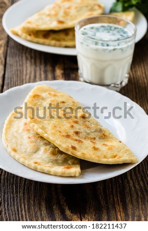 Frying pan baked flat bread on a plate with glass of sour milk. Yantyk - traditional Crimean tatar flatbread