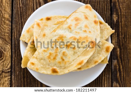 Frying pan baked flat bread on a white plate. Yantyk - traditional Crimean tatar flatbread viewed from above