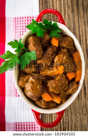 Beef stew with carrot. Traditional french beef goulash in red ceramic pot viewed from above