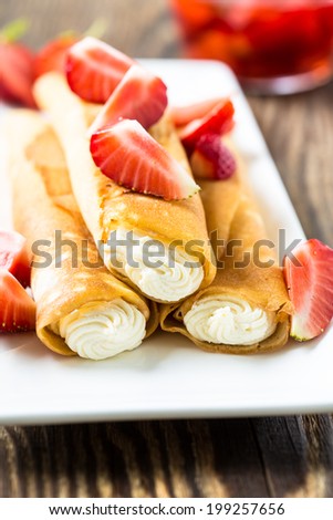 Crepes stuffed with cheese  and strawberry topping on a white plate