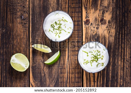 Raw  lime cheesecake in a glass on wooden table viewed from above. Rustic background with free text space