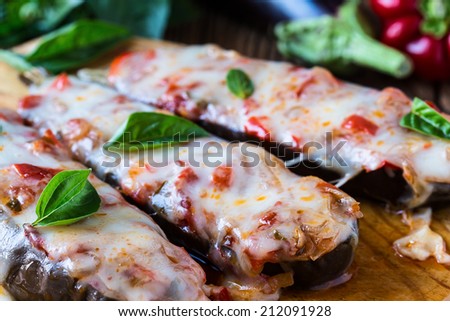 Baked stuffed eggplant with cheese and tomatoes on rustic wooden table, vegetarian food