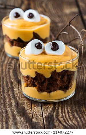 Halloween treats, little monster dessert with chocolate cookies and pumpkin mascarpone cream  topped with big marshmallow eyes