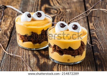 Halloween treats, little monster dessert with chocolate cookies and pumpkin mascarpone cream  topped with big marshmallow eyes