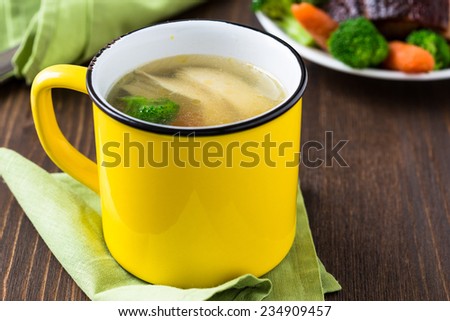 Homemade hot chicken soup in yellow mug for winter