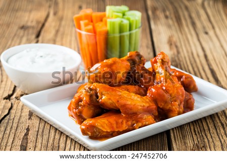 Buffalo chicken wings with cayenne pepper  sauce served hot with celery sticks and carrot sticks with blue cheese dressing for dipping